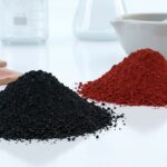 A macro shot of pure black iron oxide ceramic pigment powder in a lab setting, next to red iron oxide, showcasing its fine, matte texture for use in glazes and clay.