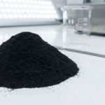 A mound of fine black iron oxide for paint, a high-purity pigment powder, shown in a clean laboratory setting to highlight its industrial quality.