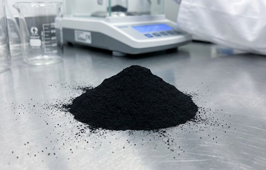 A macro shot of a mound of fine iron oxide black pigment for concrete, displayed in a clean lab setting to show its high purity and quality.